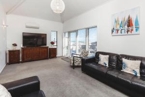 a living room with a black leather couch and a flat screen tv at Holiday On Hamblyn in New Plymouth