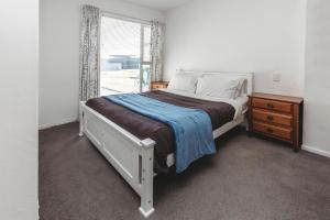 a bedroom with a white bed and a window at Holiday On Hamblyn in New Plymouth