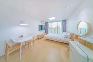1 dormitorio con cama, mesa y espejo en Zio Pinetree, en Yangyang