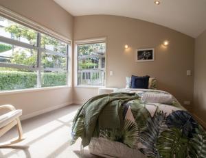 a bedroom with a bed in a room with windows at Great Location On Gilbert Central in New Plymouth