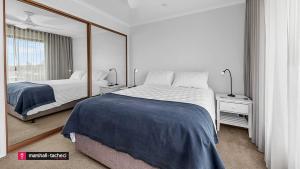 ein Schlafzimmer mit zwei Betten und einem großen Spiegel in der Unterkunft Horseshoe Beach House 4 Young Street, Bermagui in Bermagui