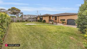 einen Hof mit einem Haus mit einem Zaun in der Unterkunft Horseshoe Beach House 4 Young Street, Bermagui in Bermagui