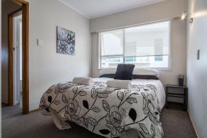 a bedroom with a bed and a large window at Sea Breeze On Belt By Coastal Walkway in New Plymouth