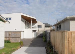 a white house with a wooden fence at By The Sea On Sackville Brand New Apartment in New Plymouth