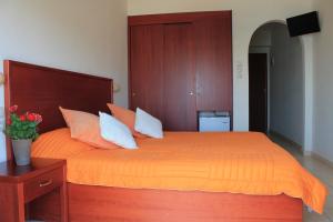 um quarto com uma cama com lençóis e almofadas laranja em Xaris em Platamon