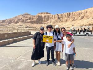 een groep mensen met een teken in de woestijn bij Royal Mountain in Luxor