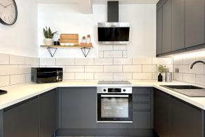 cocina con armarios grises y horno con fogones en higgihaus Apartment #56a Cool Quiet Stylish Awesome Location, en Bristol