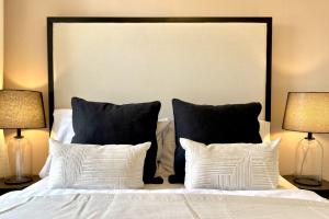 1 cama con almohadas blancas y negras y 2 lámparas en higgihaus Apartment #56a Cool Quiet Stylish Awesome Location, en Bristol