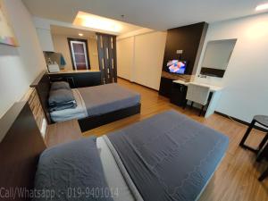 a hotel room with two beds and a television at Wan's Studio (Kota Bharu City Point) in Kota Bharu