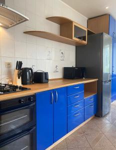 a kitchen with blue cabinets and a stainless steel refrigerator at 2 bedroom apartment close to Kaunas airport in Karmelava in Karmėlava