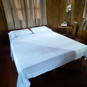 a bed with white sheets and pillows in a room at Dumaguete Treehouse in Dumaguete