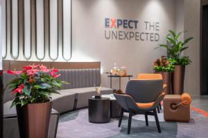 a lobby with chairs and plants and a sign that reads expect the unexpected at Holiday Inn Express Shanghai Hongqiao Linkong, an IHG Hotel in Shanghai