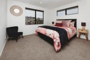 a bedroom with a bed and a chair and a window at Bell Block Beauty Brand New in New Plymouth