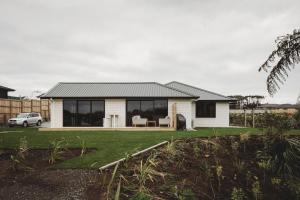 a white house with a black roof at Bell Block Beauty Brand New in New Plymouth