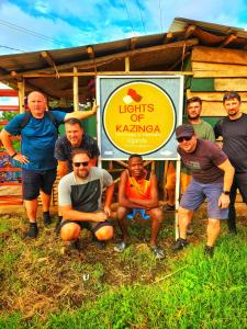 a group of people standing in front of a sign at Lights of kazinga orphanage and homestay in Rubirizi