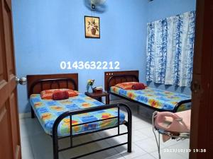 2 camas en una habitación con paredes azules en Ekaira homestay en Tambun