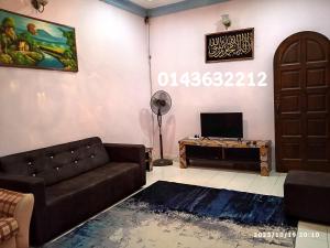sala de estar con sofá y TV en Ekaira homestay, en Tambun