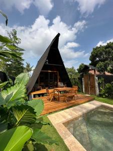 a thatched hut with a pool in front of it at Villa Verde the garden in Kejayan