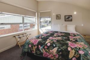 a bedroom with a bed with a floral bedspread at City Sails Central Location in New Plymouth