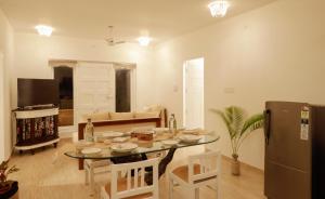 a kitchen and living room with a table and a refrigerator at Seclude Kerala, Beach House in Mararikulam