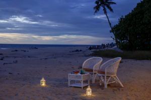 - deux chaises et une table sur la plage la nuit dans l'établissement Seclude Kerala, Beach House, à Mararikulam