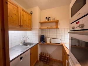 a small kitchen with wooden cabinets and a sink at Appartement Méribel, 2 pièces, 5 personnes - FR-1-355-247 in Les Allues