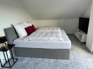 Una cama con sábanas blancas y almohadas rojas en un dormitorio. en Apartment mit Weitblick, 