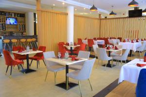 a restaurant with white tables and red chairs at Black Horse Hotel in Addis Ababa