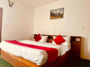 a bedroom with two beds with red and white pillows at Hotel Alpine in Manāli