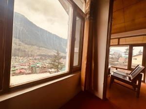 a room with a window with a view of a city at Hotel Alpine in Manāli