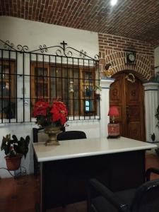 a room with a table with a vase with red flowers at Hotel Nolasco in Antigua Guatemala