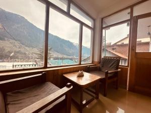 a room with a table and chairs and a large window at Hotel Alpine in Manāli