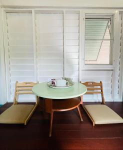 einen Tisch und Stühle in einem Zimmer mit zwei Fenstern in der Unterkunft The Backyard 28 in Klong Toi