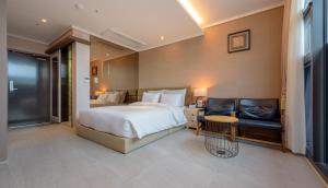 1 dormitorio con cama, mesa y sofá en Friemily Pool Villa & Hotel, en Geoje