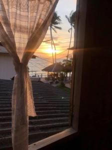 Blick auf den Sonnenuntergang von einem Fenster mit Vorhang in der Unterkunft Aforetime House @ Samui in Taling Ngam Beach