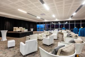 ボゴタにあるCourtyard by Marriott Bogota Airportの白い椅子とテーブル、窓が備わる客室です。