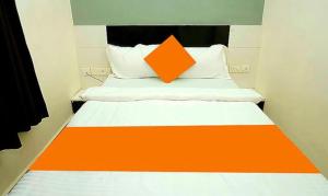 uma almofada laranja numa cama num pequeno quarto em FabHotel Ekamra Greens By Y Hotels em Bhubaneshwar