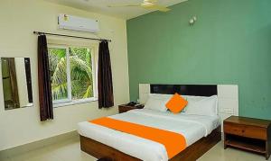um quarto com uma cama grande e uma almofada laranja em FabHotel Ekamra Greens By Y Hotels em Bhubaneshwar