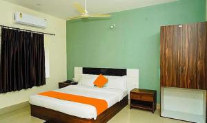 um quarto com uma cama com um edredão laranja e branco em FabHotel Ekamra Greens By Y Hotels em Bhubaneshwar