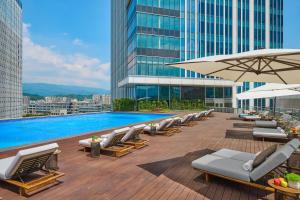 a pool with lounge chairs and umbrellas on a building at Grand HiLai Taipei in Taipei