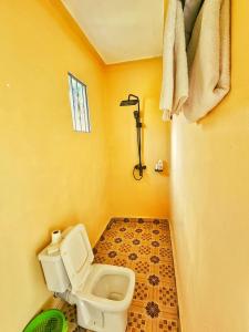 a yellow bathroom with a toilet and a shower at Lights of kazinga orphanage and homestay in Rubirizi
