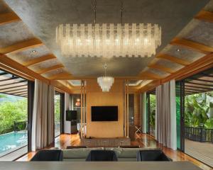 a living room with a television and a chandelier at The Hidden Village, Khao Yai in Mu Si
