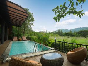 a swimming pool on a deck with chairs at The Hidden Village, Khao Yai in Mu Si