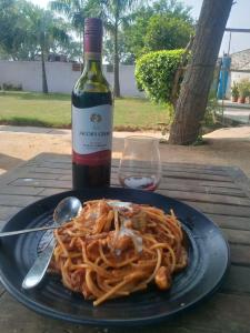 un plato de espaguetis en una mesa con una botella de vino en Backpackers Village Agra en Agra