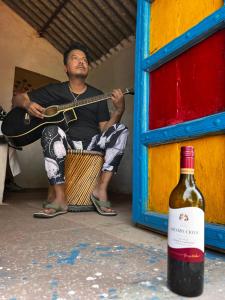a man playing a guitar and a bottle of wine at Backpackers Village Agra in Agra