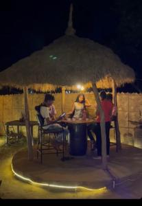 a group of people sitting at a table under an umbrella at Backpackers Village Agra in Agra