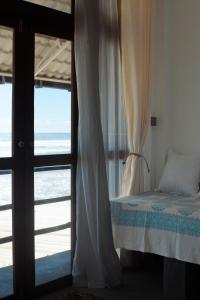 Schlafzimmer mit Meerblick durch eine Glastür in der Unterkunft Marshmellow Beach Rooms - Sri Lanka in Ahangama