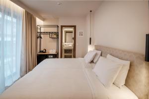 a bedroom with a large white bed with a window at IRA - ΗΡΑ Hotel in Kalamata