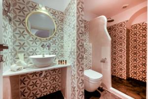 ein Badezimmer mit einem Waschbecken, einem WC und einem Spiegel in der Unterkunft Sigalas Beach Hotel in Kamari