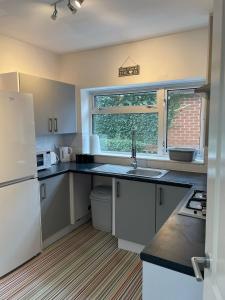 a kitchen with white cabinets and a sink and a window at Little Manor in Chesterfield